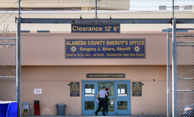 A blue door framed by a fence with a sign at the top saying "Alameda County Sheriff's Office"