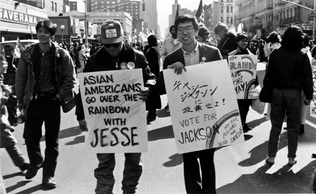Two men hold signs at a rally in a black and white photo.