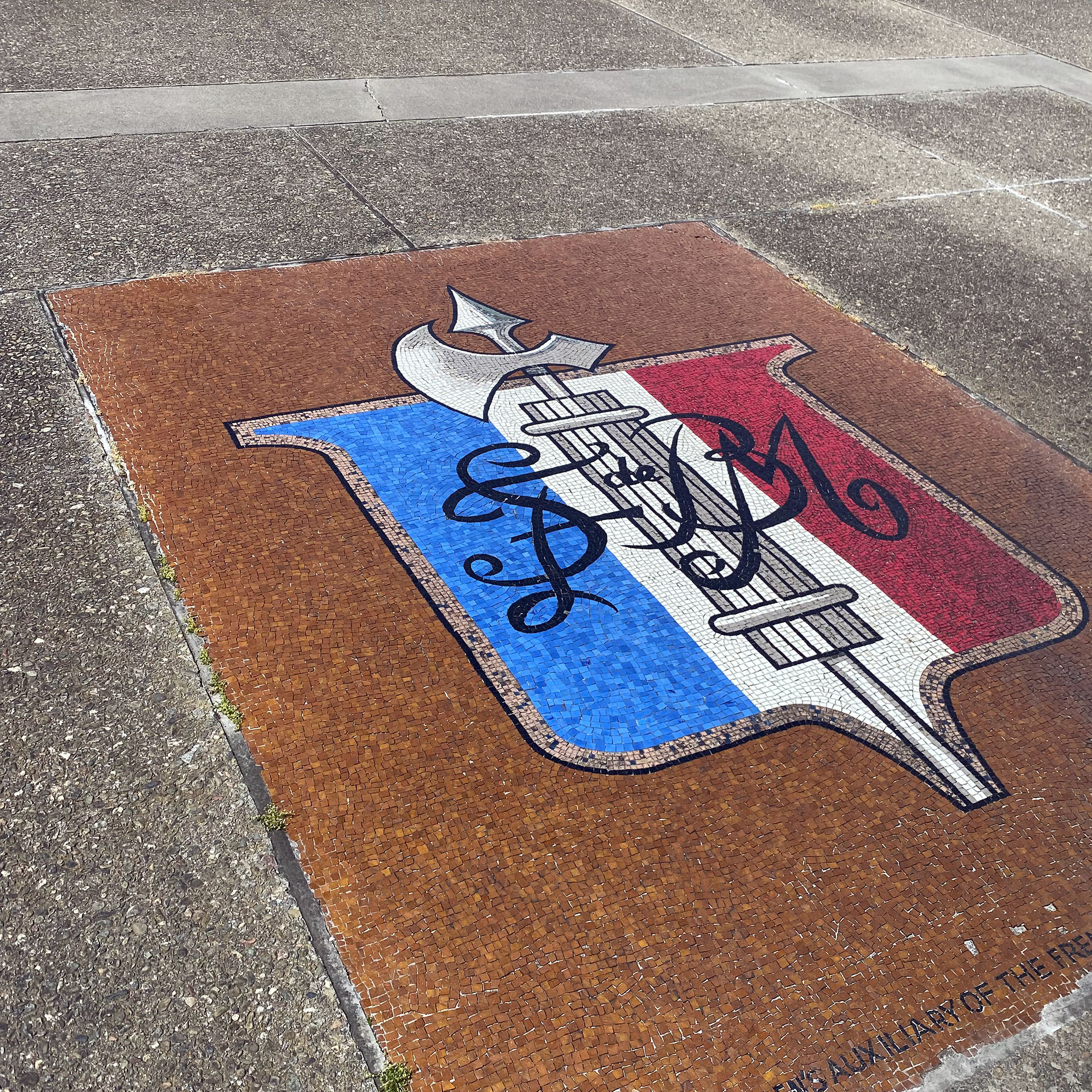 A mosaic is inlaid in the ground showing a blue, white and red crest depicting a syringe