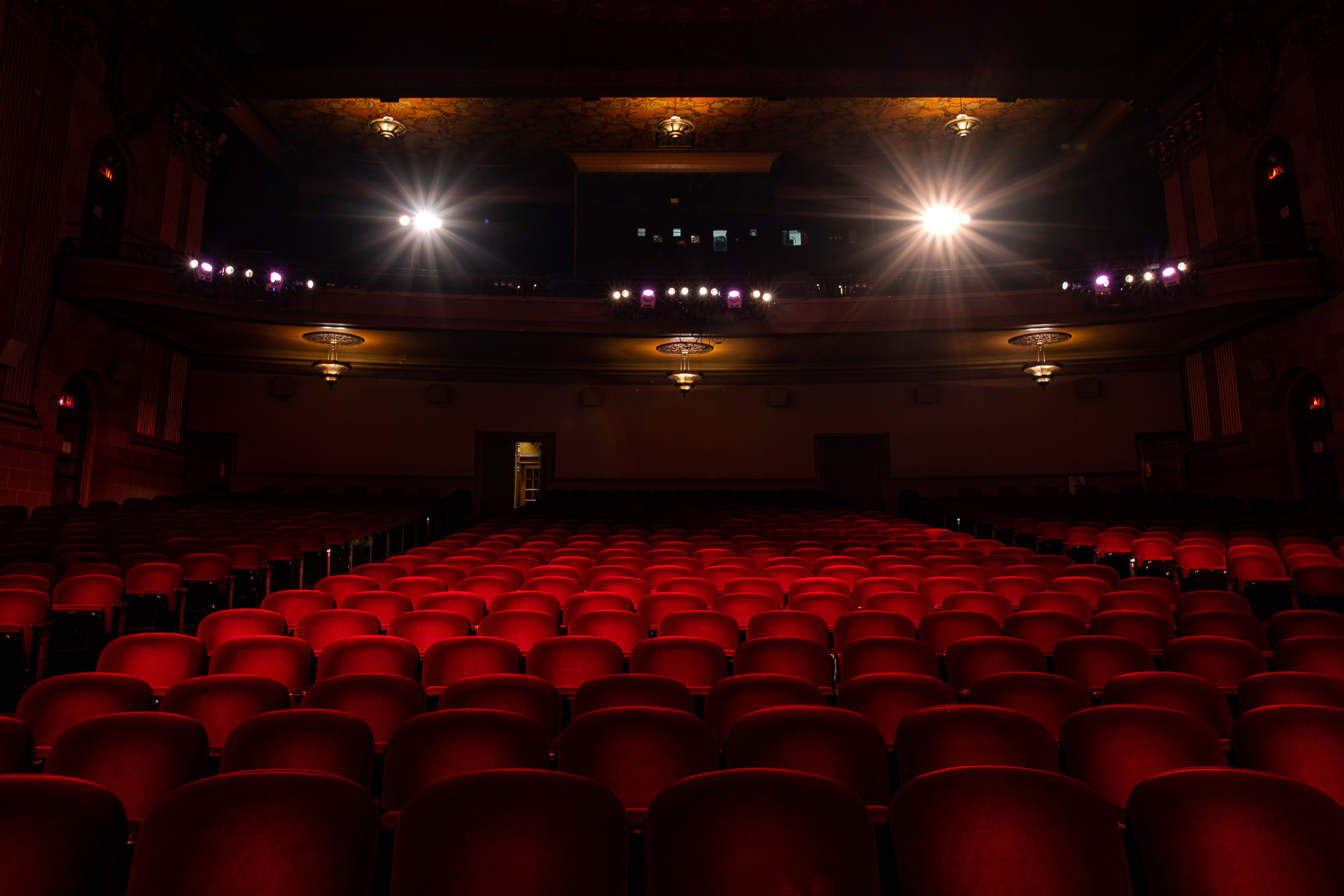Rows of red velvet seats in a dimmed theater.
