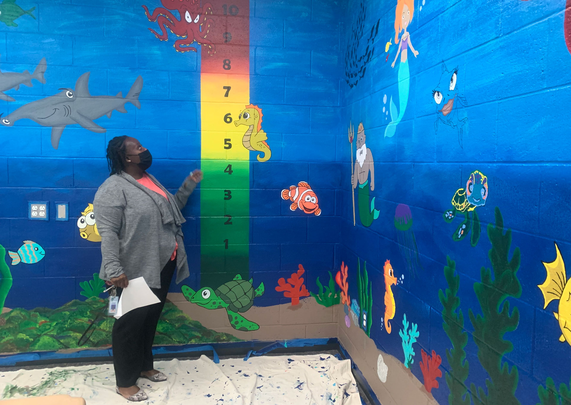 woman stands inside room painted to look like the inside of an aquarium