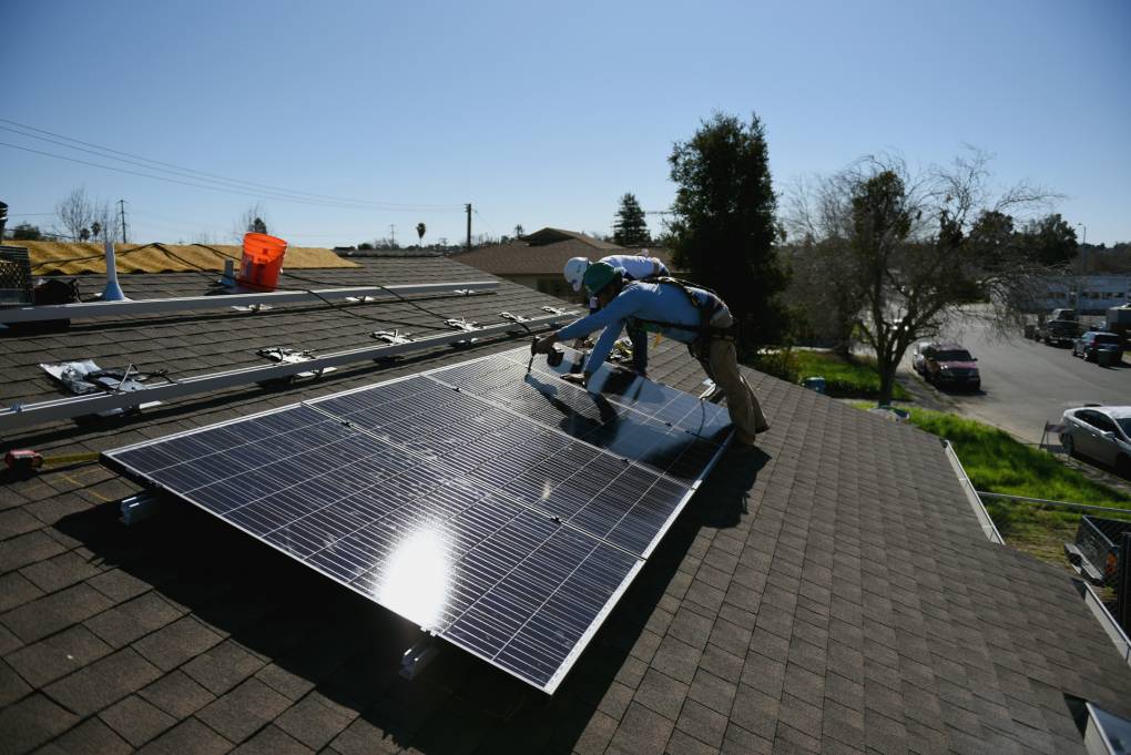 Andrew Hayes, an employee of Grid Alternatives, and Nancy Quiros, a volunteer, install solar panels to a home in Vallejo, Calif., on February 13, 2018.