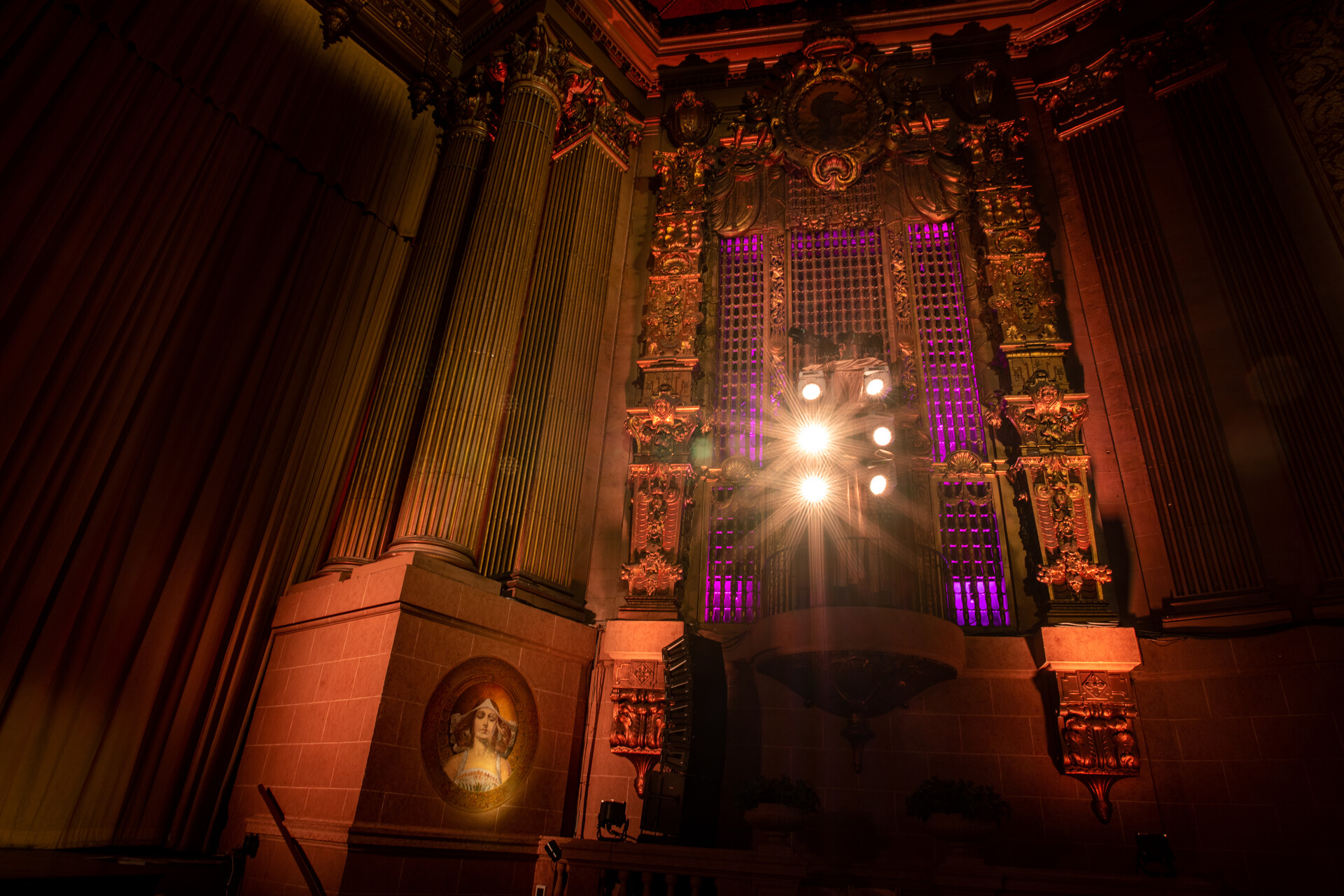 The proscenium of the Castro Theatre, taken from below.  The lighting is purple and gold.
