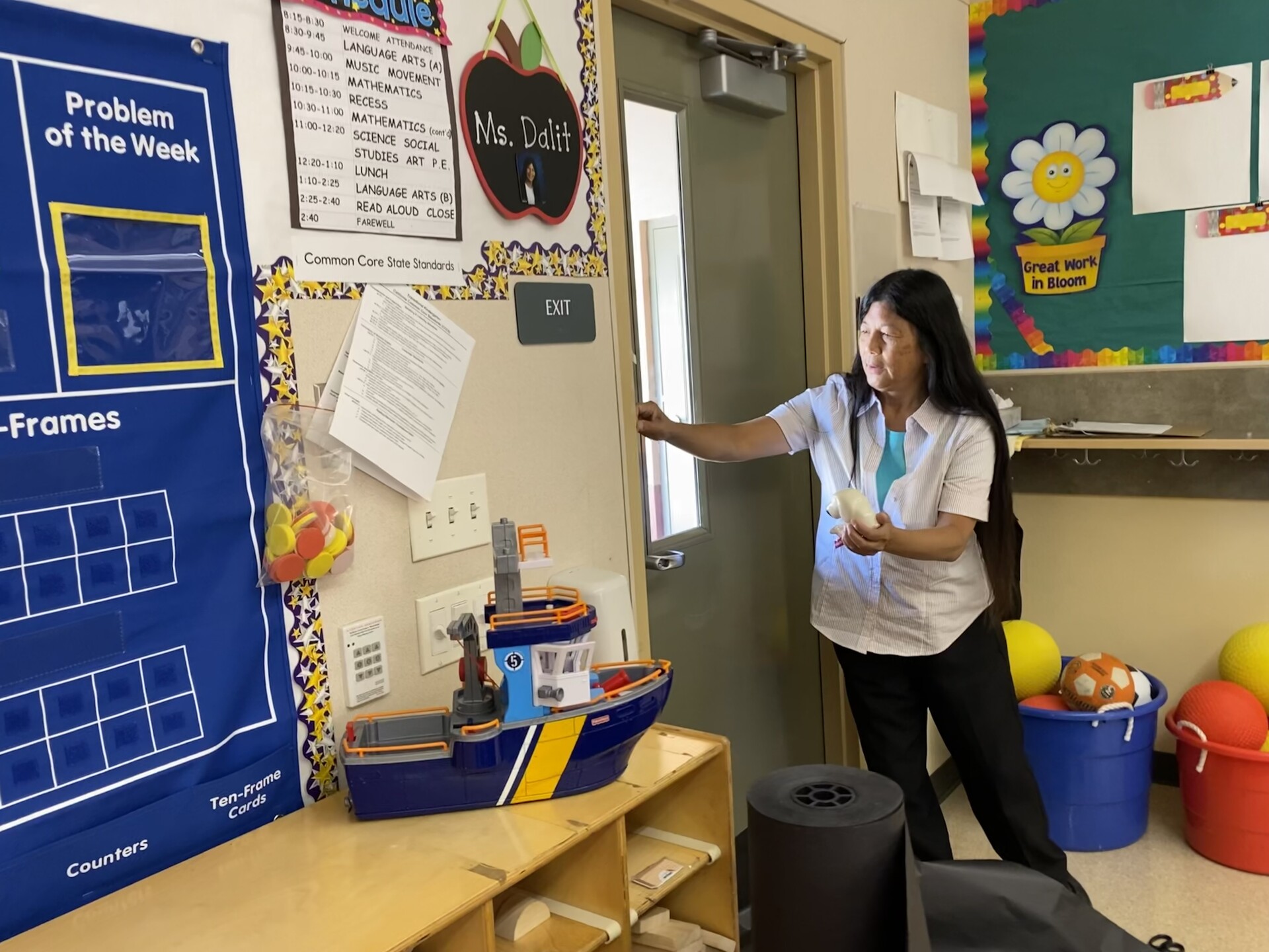 a woman with black hair prepares an elementary school classroom with colorful decorations