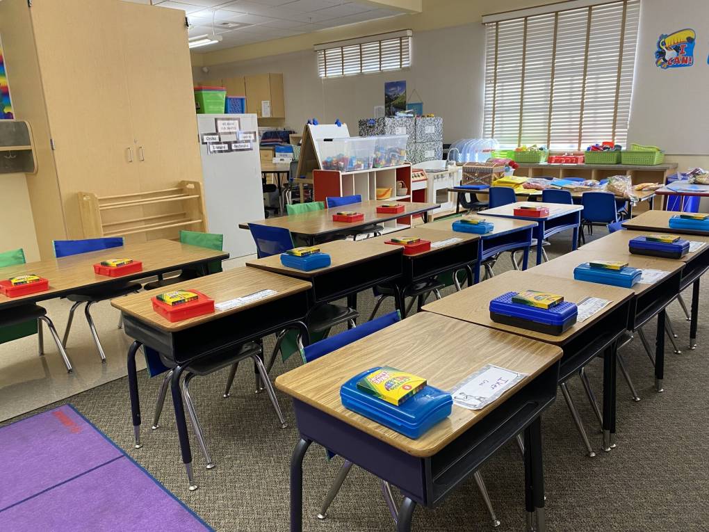 children's desks with supplies on them in a classroom
