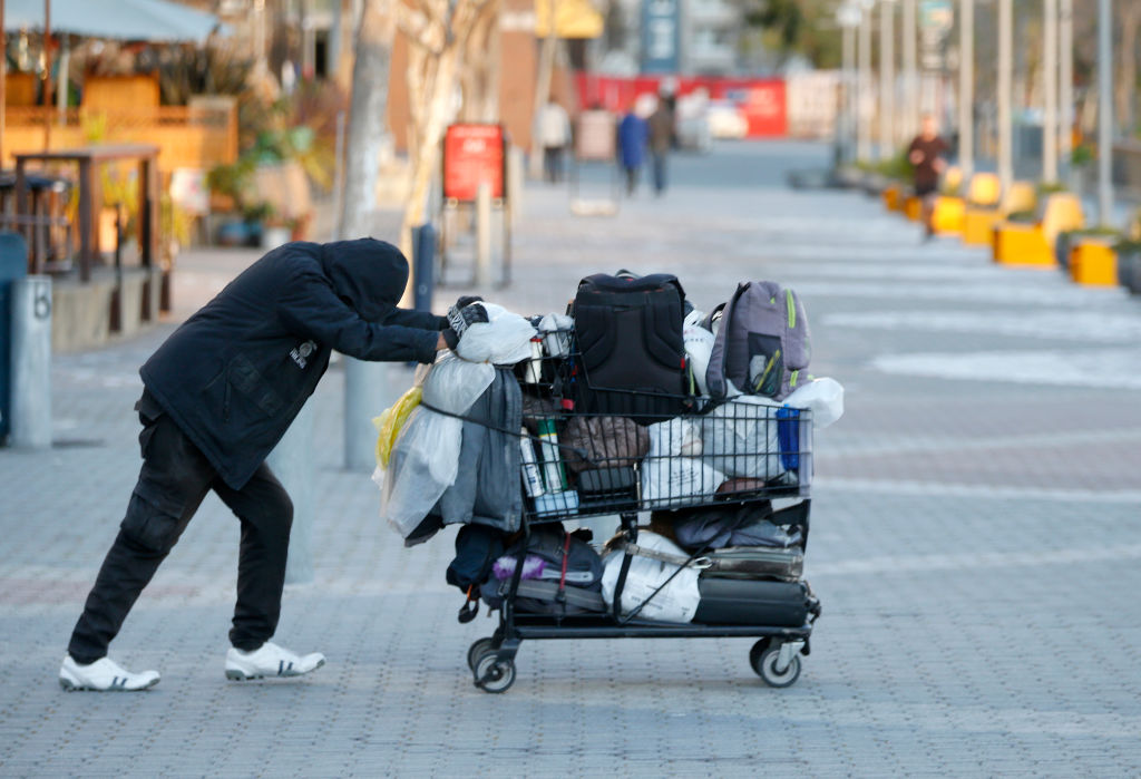 a man in a dark jacket pushes a shopping cart
