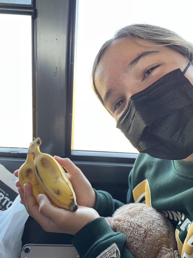 A person wearing a mask holding bananas.