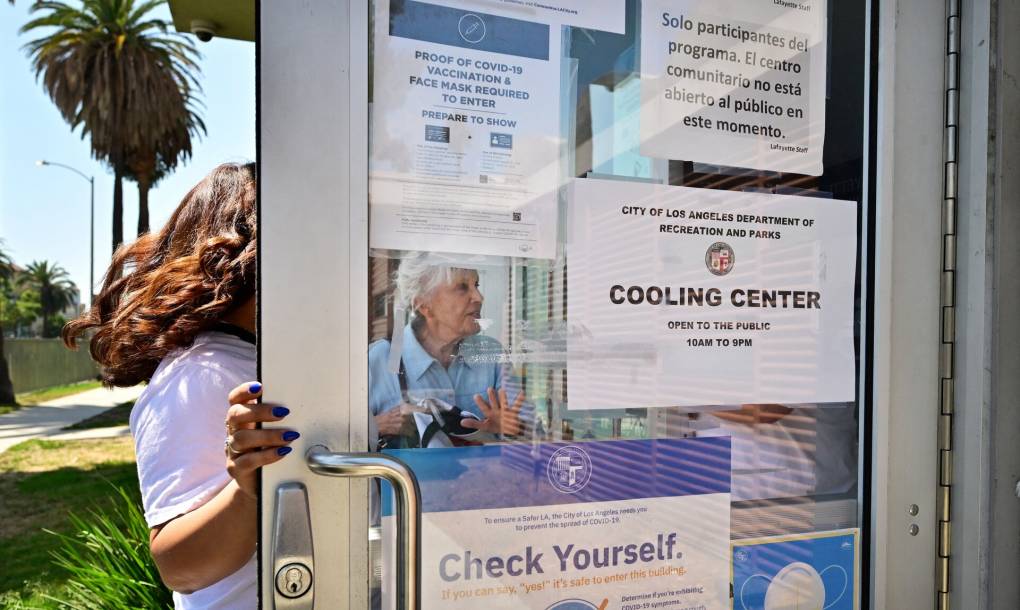 A door to a cooling center is open with signs saying 'cooling center' and two women about to enter.