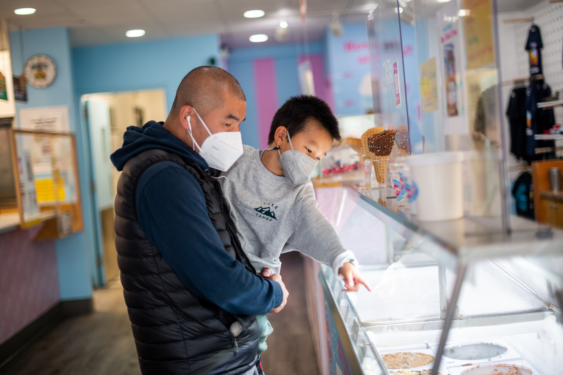 a man holds a little boy as they pick out an ice cream flavor