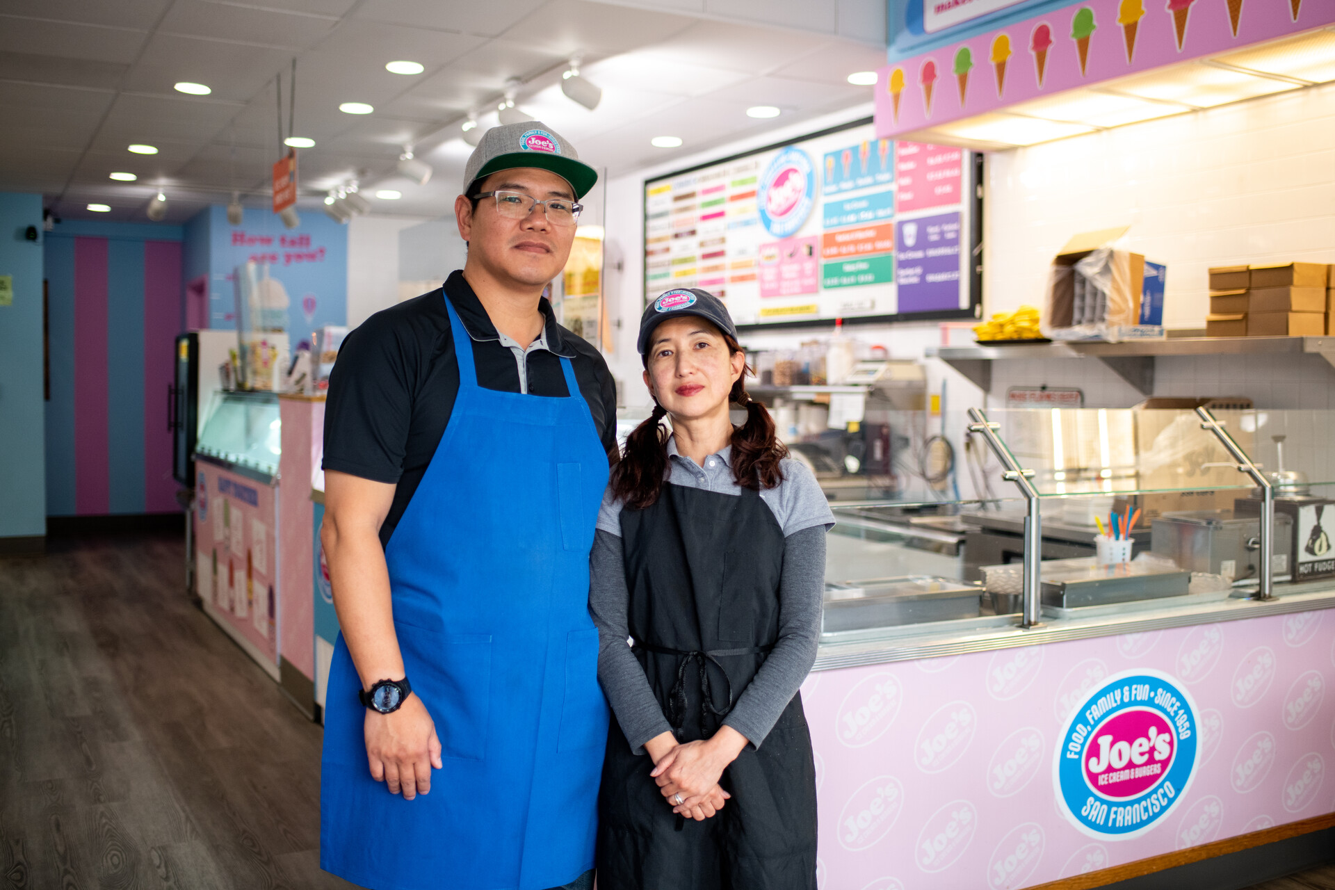 a man and woman stand in front of their ice cream shop