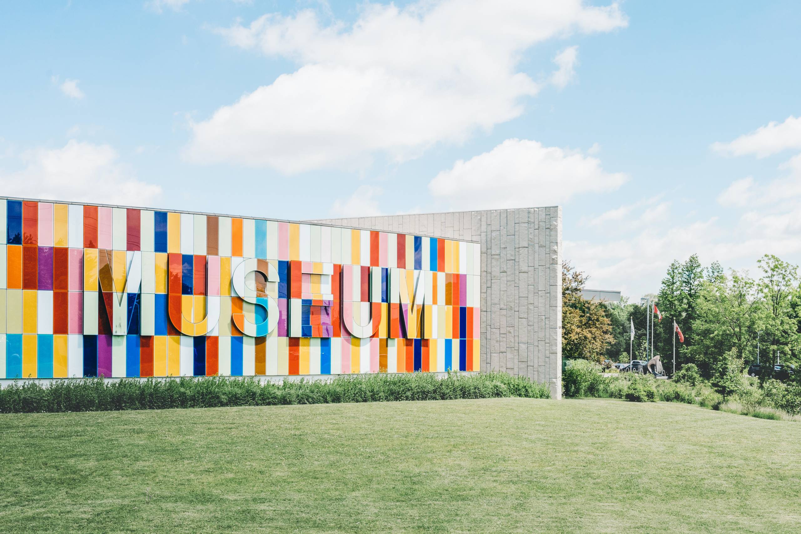 An image of a multicolored museum sign on a grassy surface during the day.