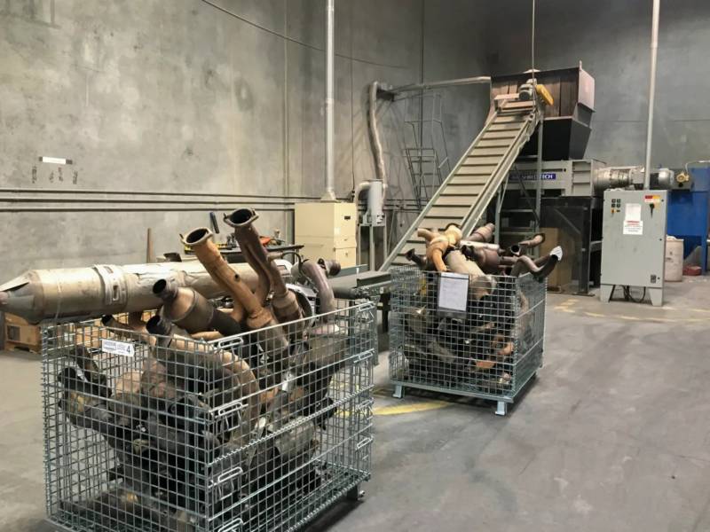 piles of catalytic converters in containers at a warehouse