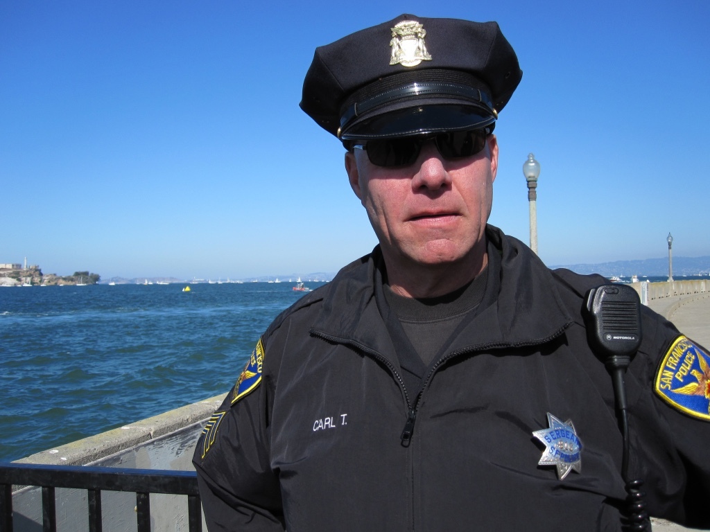An SFPD police officer in full uniform looks at the camera.