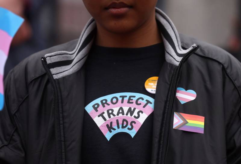 a person wears a shirt that reads 'protect trans kids'