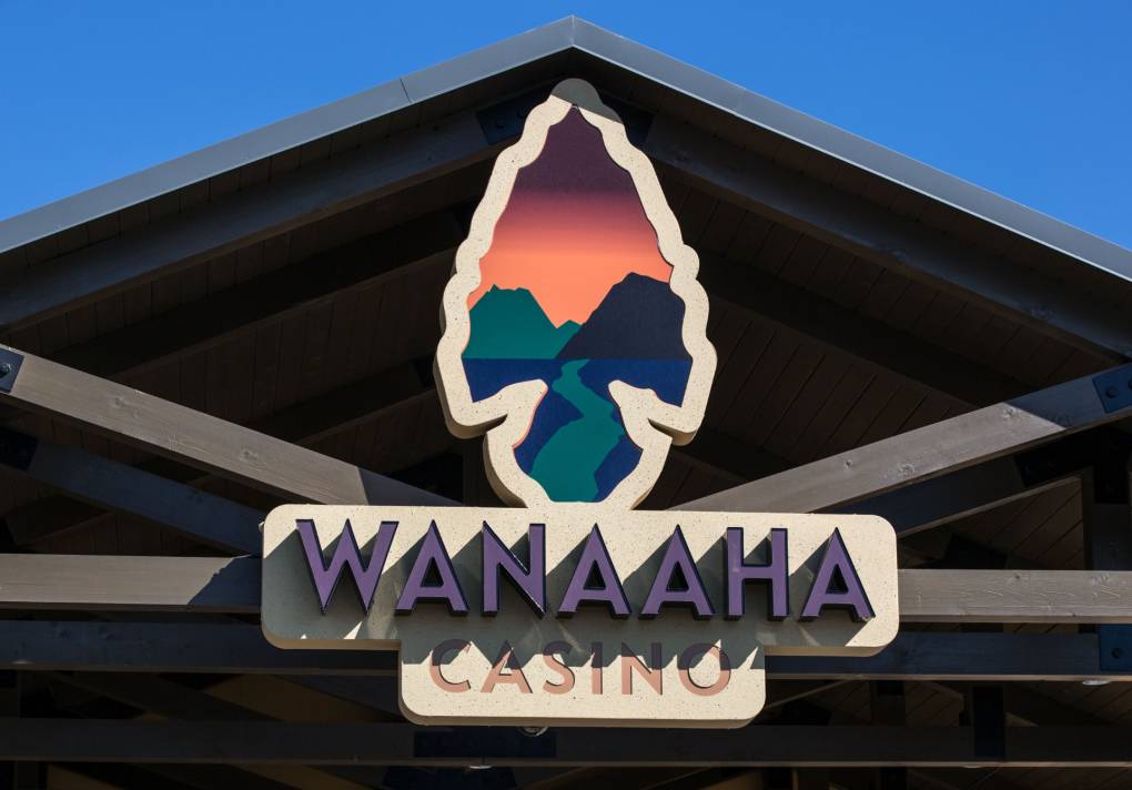 The sign of a casino shows an arrowhead with a graphically stylized sunset and mountains inlaid in it, above text reading "WANAAHA CASINO."