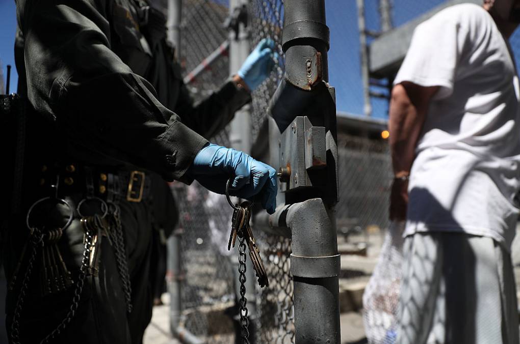 a man in a prison uniform unlocks a gate for an inmate