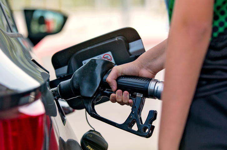 A woman operates a gasoline pump as she fills her tank with gas.