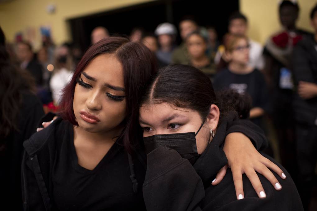two young Latina women with their arms around each other at a vigil