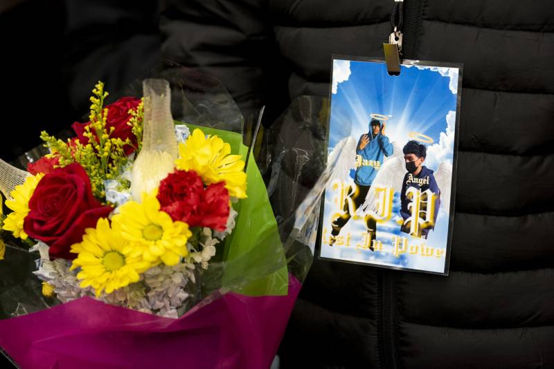 a bouquet of red and yellow flowers and card depicting two young Latino boys as angels