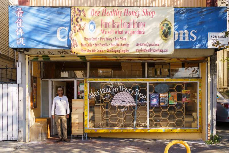 a man stands in front of a storefront with honeycomb and honey products