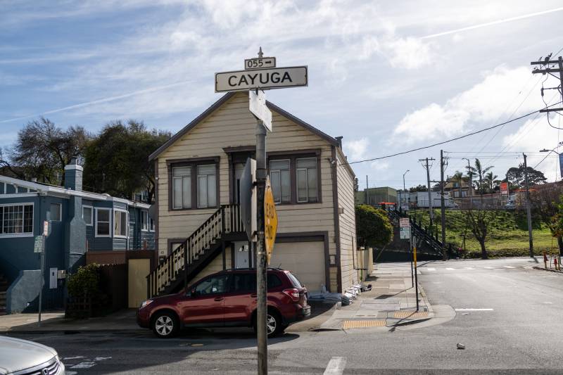 A street sign that reads "Cayuga" in a residential neighborhood.