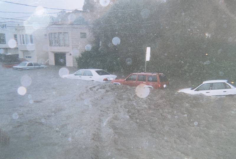A vintage image of cars underwater on a residential street.