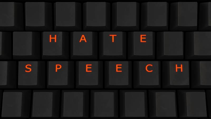 A close up of illuminated glowing keys on a black keyboard spelling "Hate Speech" as a 3D illustration.