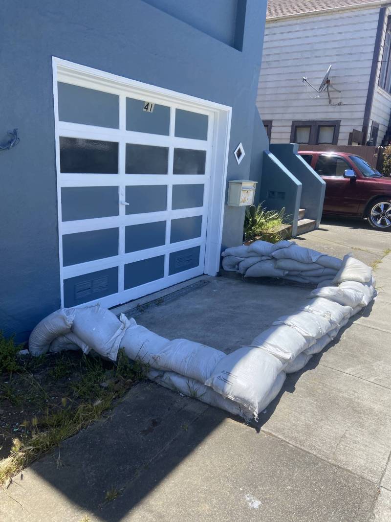 A garage attached to a house with sandbags placed in front.