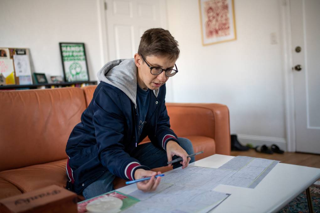 a woman sits on a couch working on election canvassing maps
