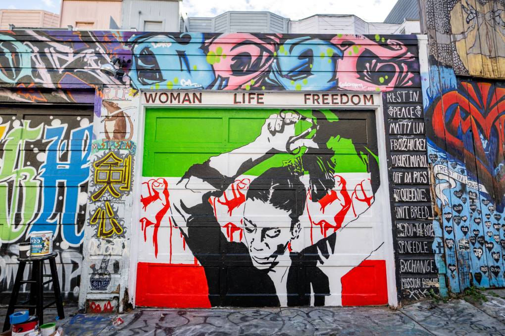 Mural of a silhouette of a woman with the Iranian flag in the background. And the words ' women, life, freedom' at the top.