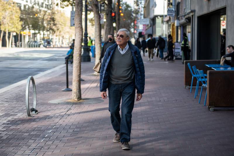a man in sunglasses walks down a city street