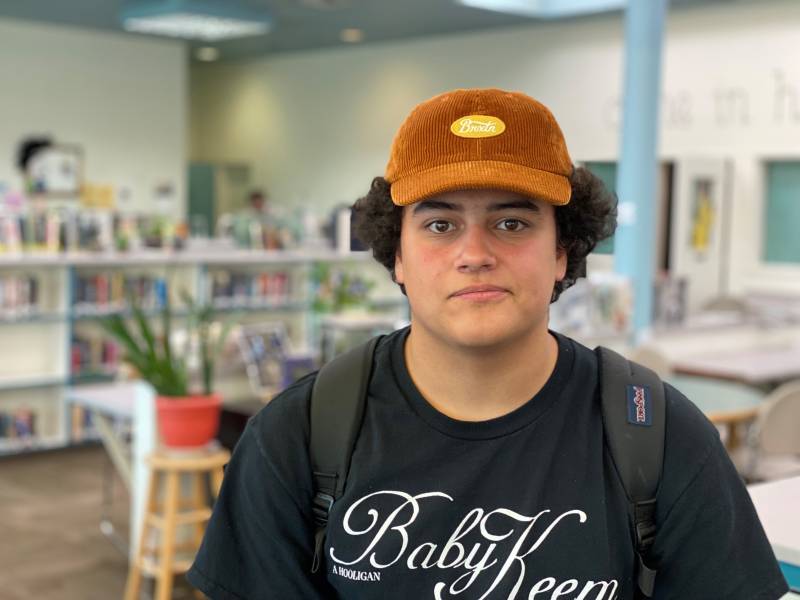 a young man in a ball cap stands in a library