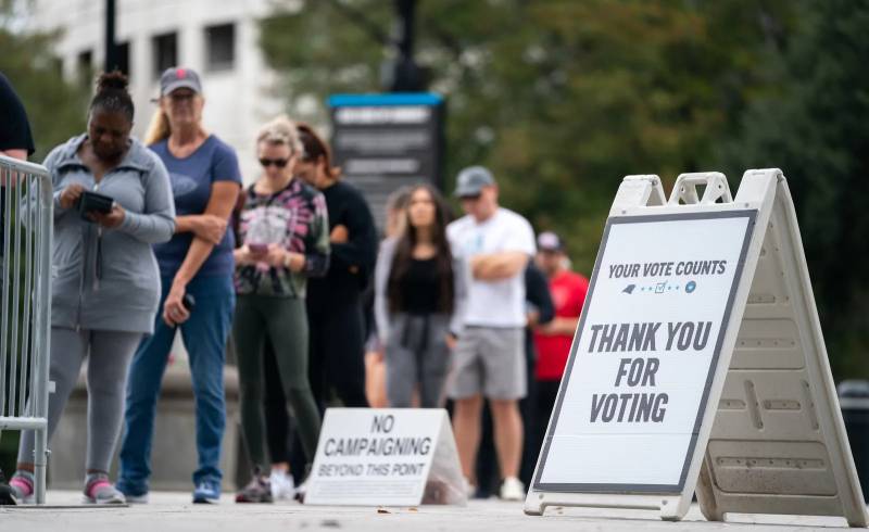 people wait line to vote at a polling place