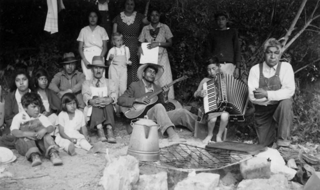 a black and white photograph of a large Native American family circa 1930s, with musical instruments