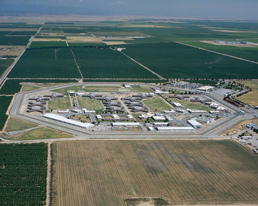 An aerial view of a prison facility surrounded by green fields.