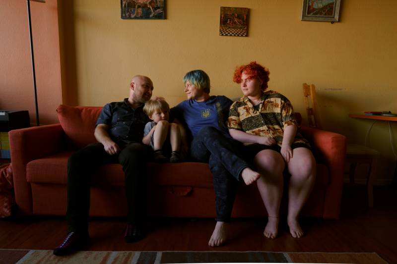 A husband and wife with their two children sit on a couch together.