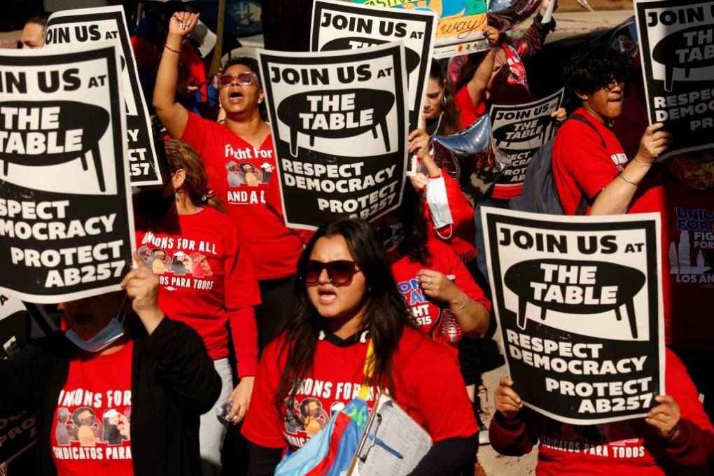 Workers protest with signs that read "Join us at the table, respect democracy, protect AB257"