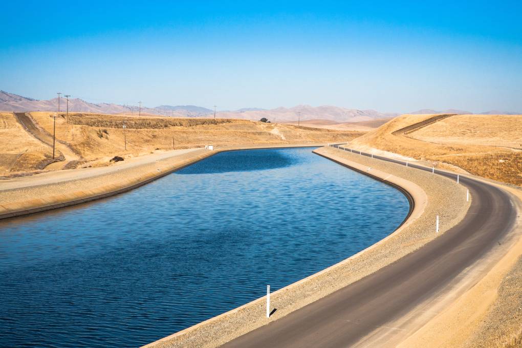 An aquaduct with flowing water and desert on both sides.