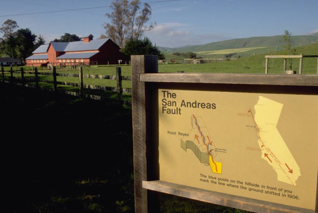 A sign outside a farm that has a map of the San Andreas Fault trail.