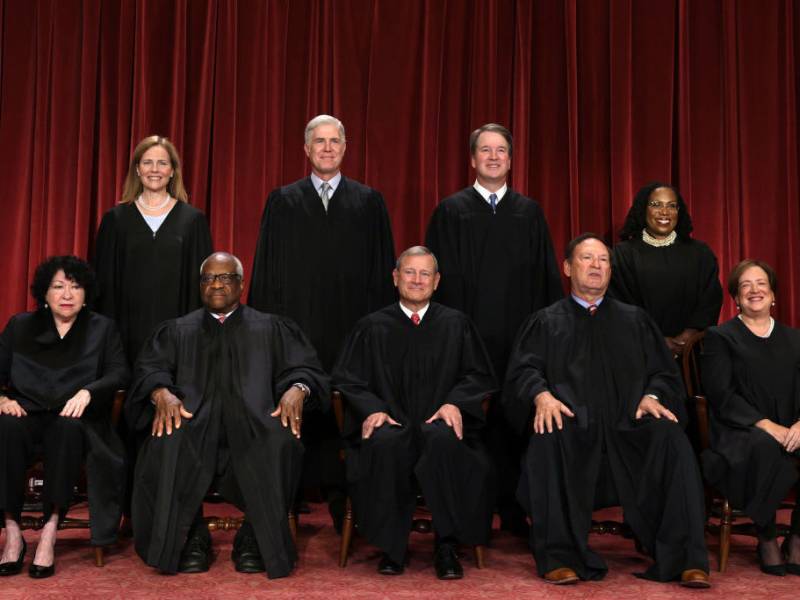 Nine people wearing black robes sit and stand for a photo.