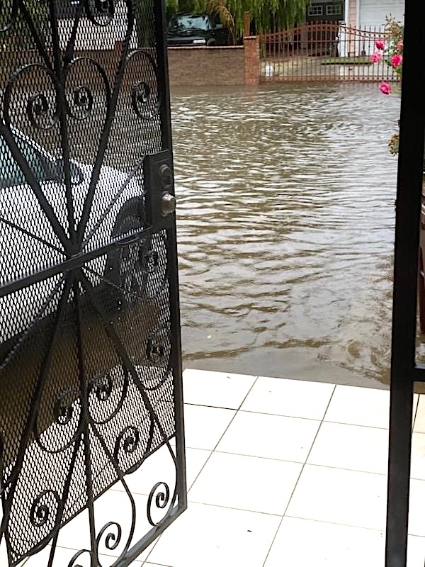 A front door opens onto a flooded street