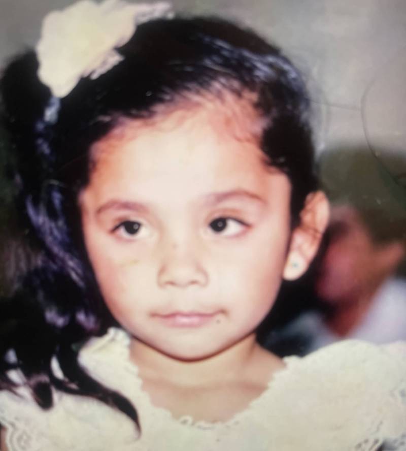 The image of a young Latina girl of kindergarten age wearing a white dress.