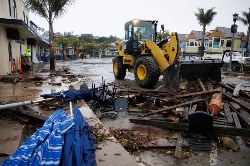 A bulldozer in a flood battered neighborhood removes debris.