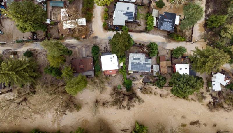 A bird's eye view of houses with flood waters flowing between them.