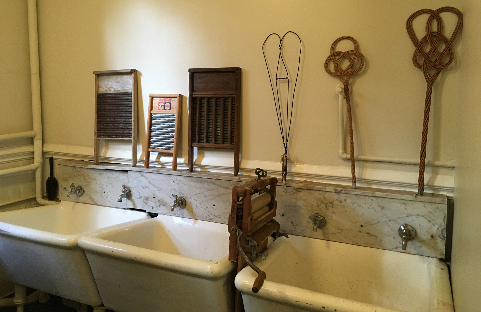 A laundry room in a 1880s Victorian house. It includes three wash basins, a wringer and a washboard.
