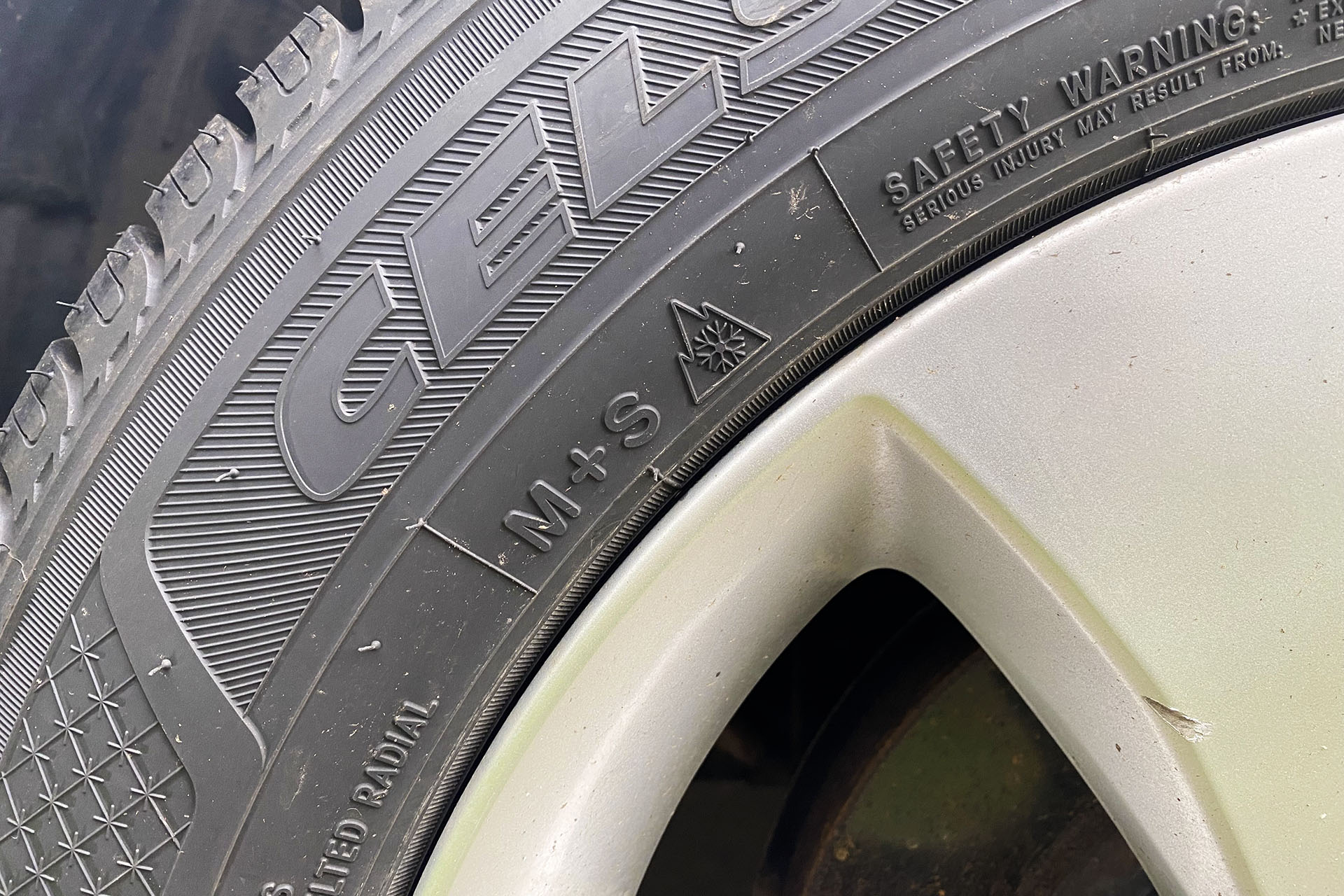 A closeup photo of a car tire, with markings on it.