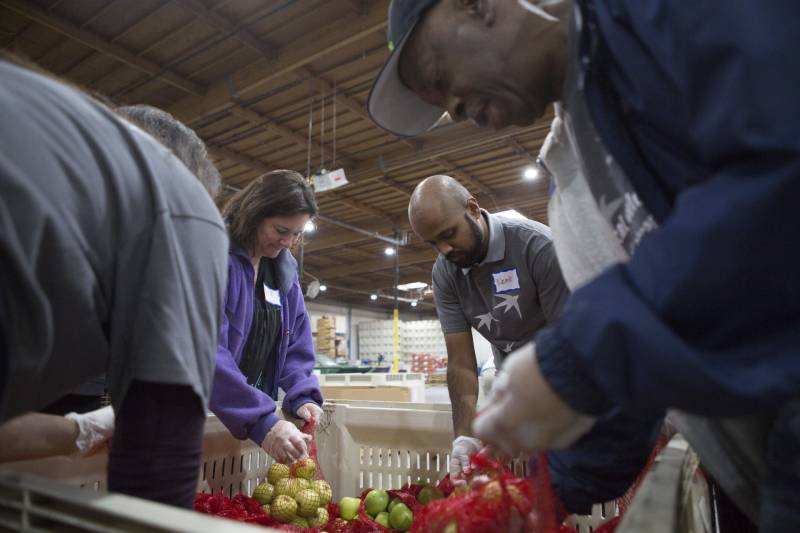 Four people sort apples in a food bank.