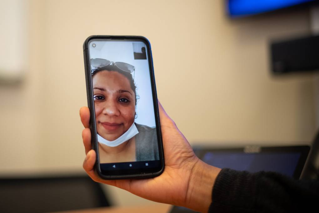 The image of a Latina woman on a phone being held by someone else.