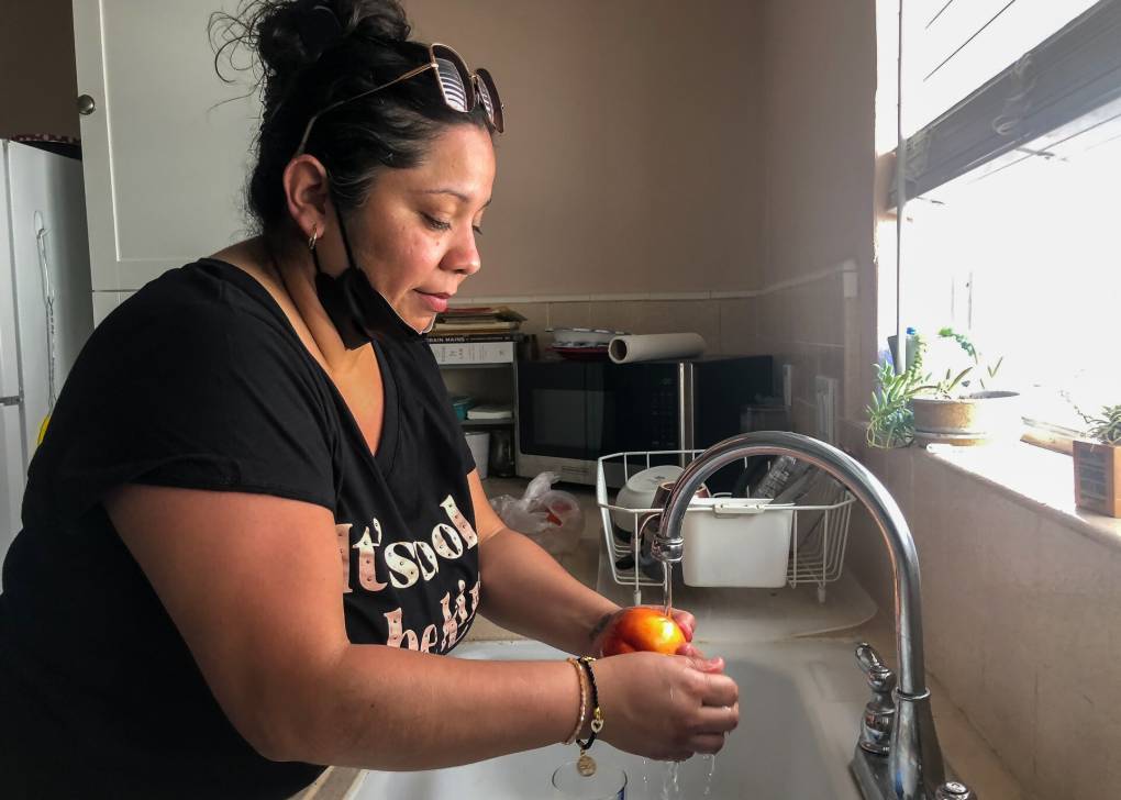 A Latina woman washes her hands in a kitchen sink.