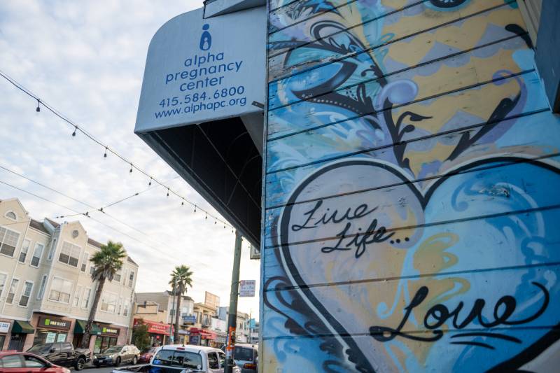 a mural that says "live life love" is seen on the side of a building labeled "alpha pregnancy center"